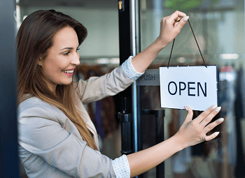 Woman small business owner puts an open sign on storefront